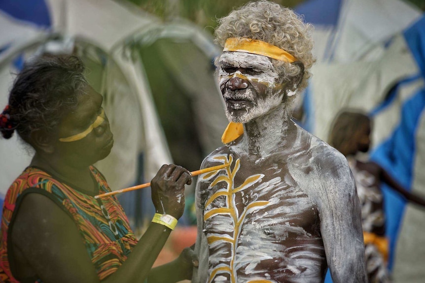 Aboriginal man Eddie William Gumbula is painted in white and yellow body paint as he prepares to perform at the Gama Festival.