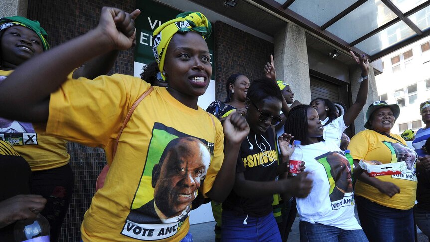 Women wearing t-shirts printed with Cyril Ramaphosa sing and dance.