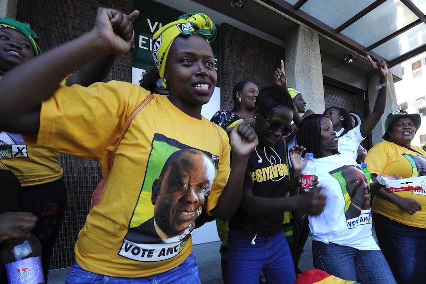 Women wearing t-shirts printed with Cyril Ramaphosa sing and dance.