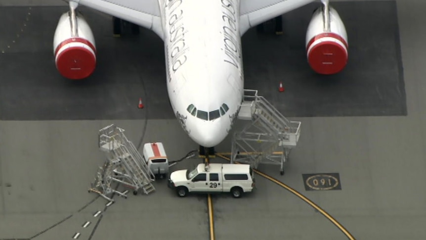 A close up of a truck blocking a Virgin Australia plane at Perth airport.