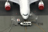 A close up of a truck blocking a Virgin Australia plane on the airport tarmac.