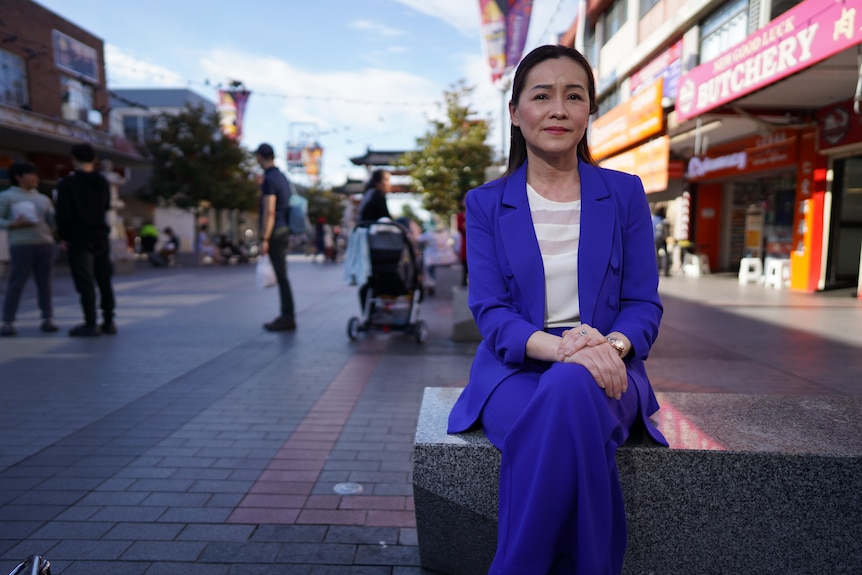 A woman sitting in a purple suit on a street