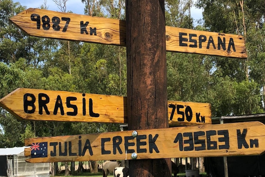 A sign post explaining the kilometres to a variety of towns and countries, including Julia Creek 13563km.
