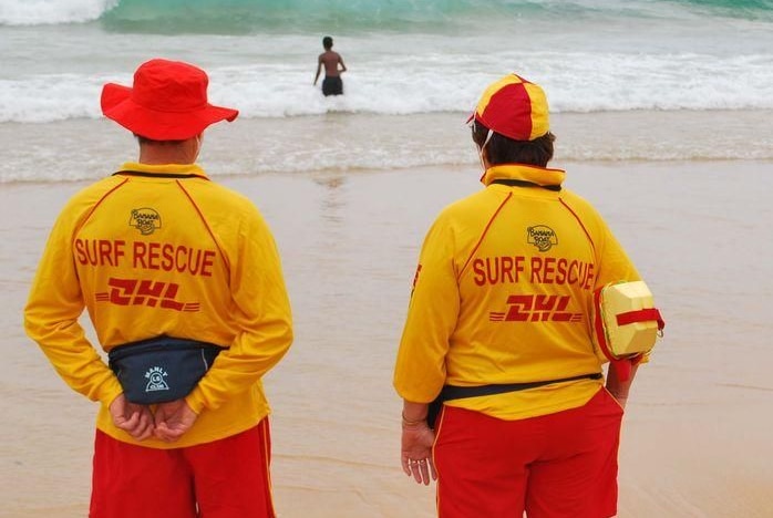 Two lifesavers watch on as people swim in the beach