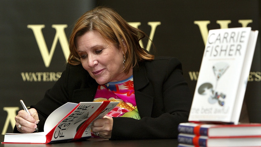 Carrie Fisher autographs one of her books