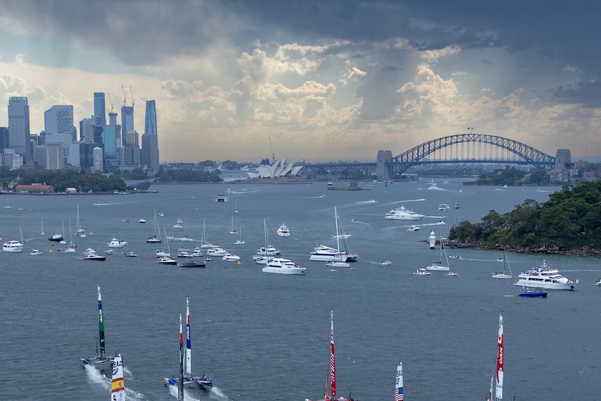 Storm clouds over sydney's harbour with sail boats in the foreground. 