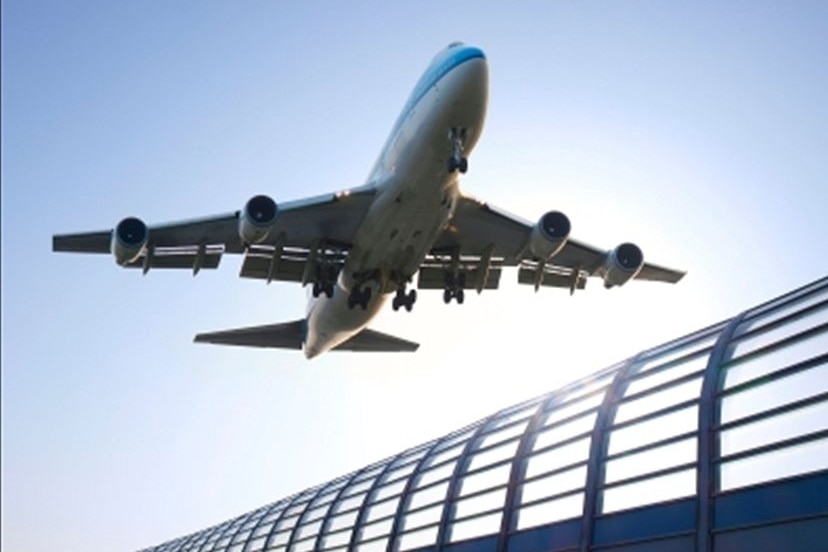 An aeroplane taking off above a building