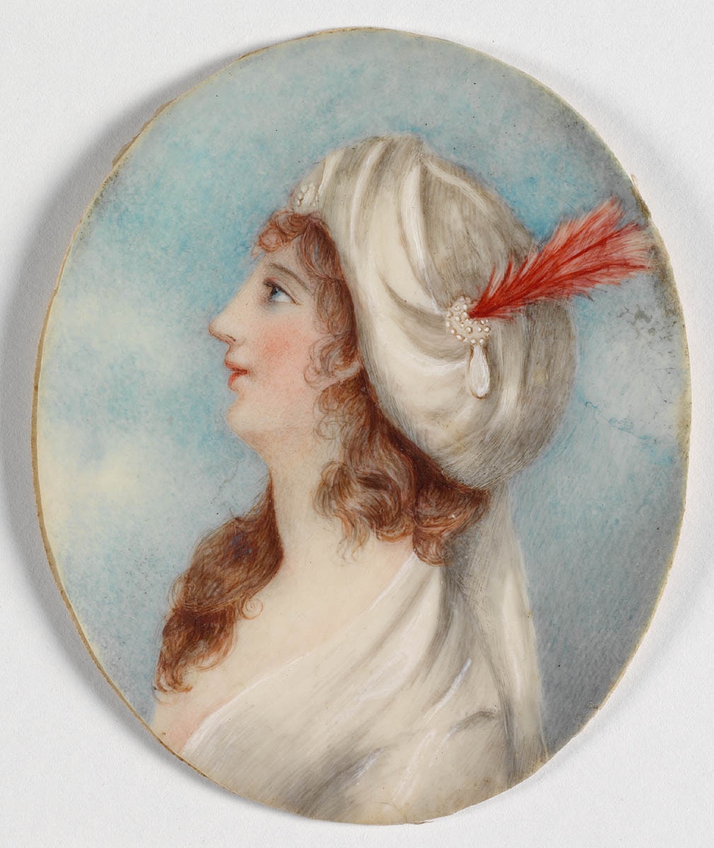 Tiny brooch with a portrait of a fair skinned woman with red curls 