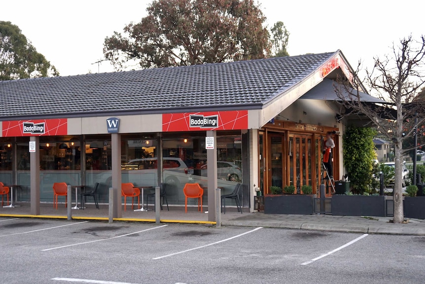 An external photo of the cafe, which has red and black chairs and a front courtyard.