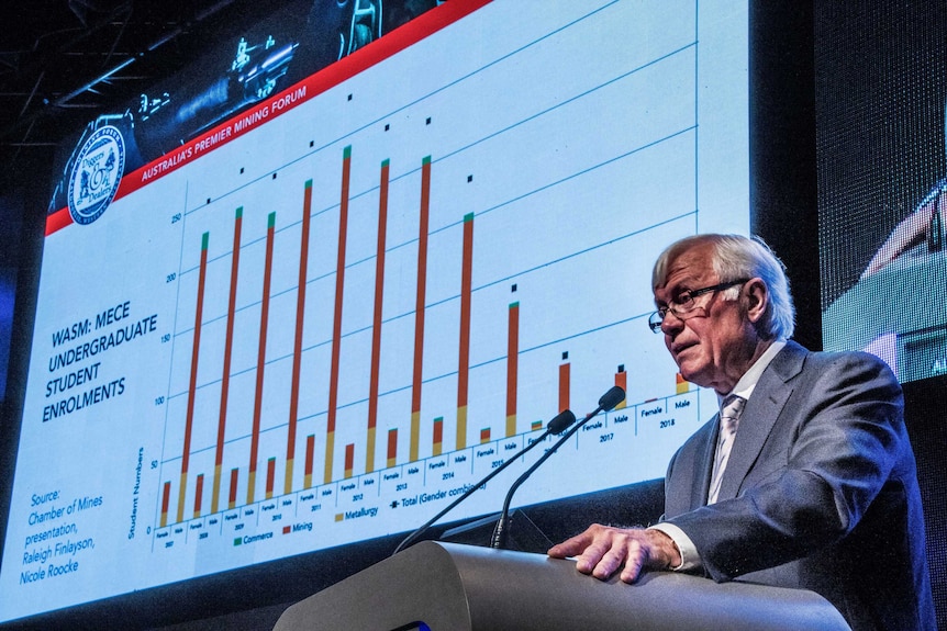 A mining executive with grey hair making a speech on a stage