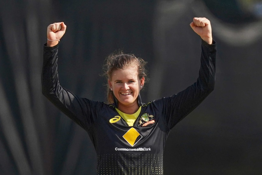Jess Jonassen celebrates by holding her arms above her head with clenched fists and smiling