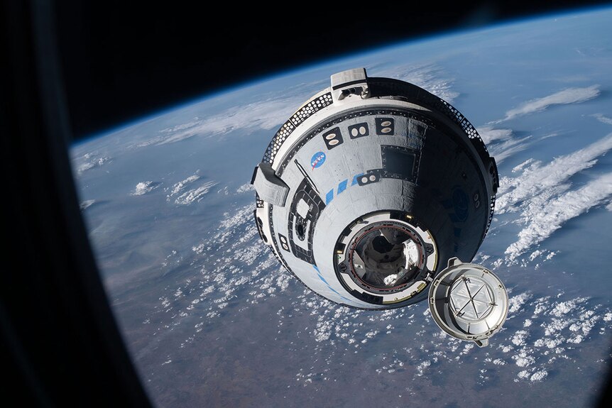 A conical capsule space capsule above the Earth approaches the camera.