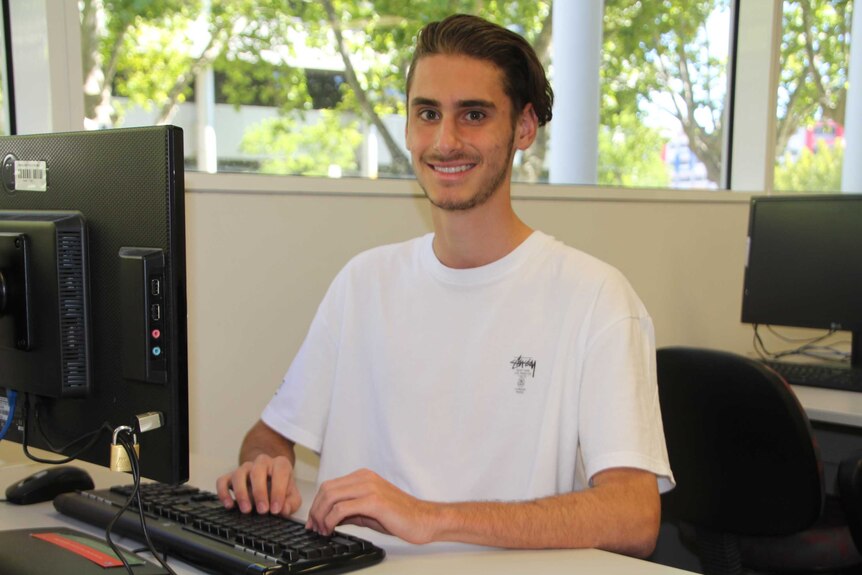 Michael Pappas sits at a desk at TAFE in front of a computer.