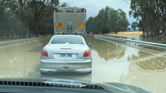 A car and a truck trapped in flood waters on the Hume Freeway through the windscreen of another car.