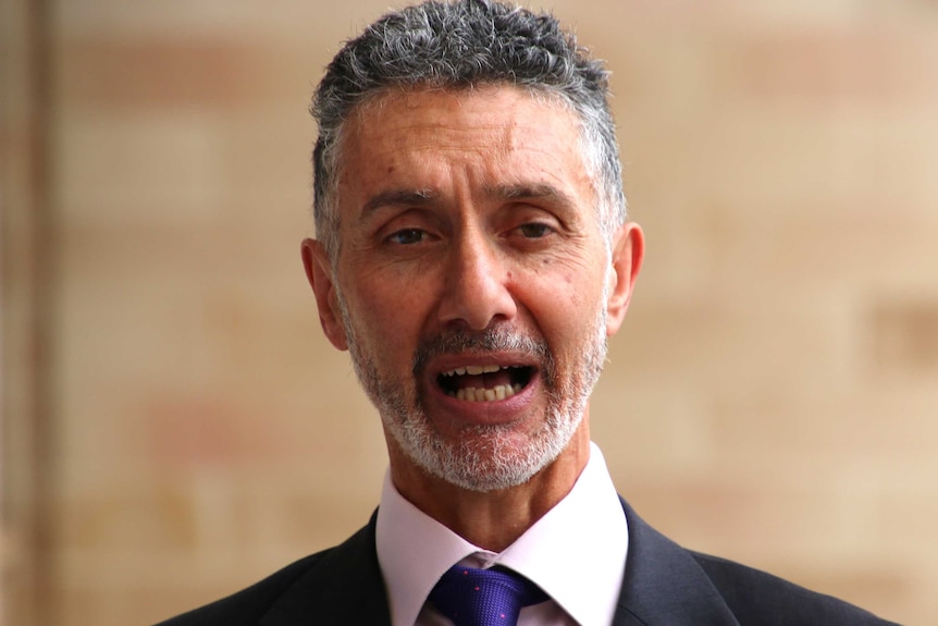 A tight head and shoulders shot of Labor MP Tony Buti in a suit talking outside the WA Parliament.