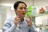 He Jiankui gestures with his hands while speaking during an interview.