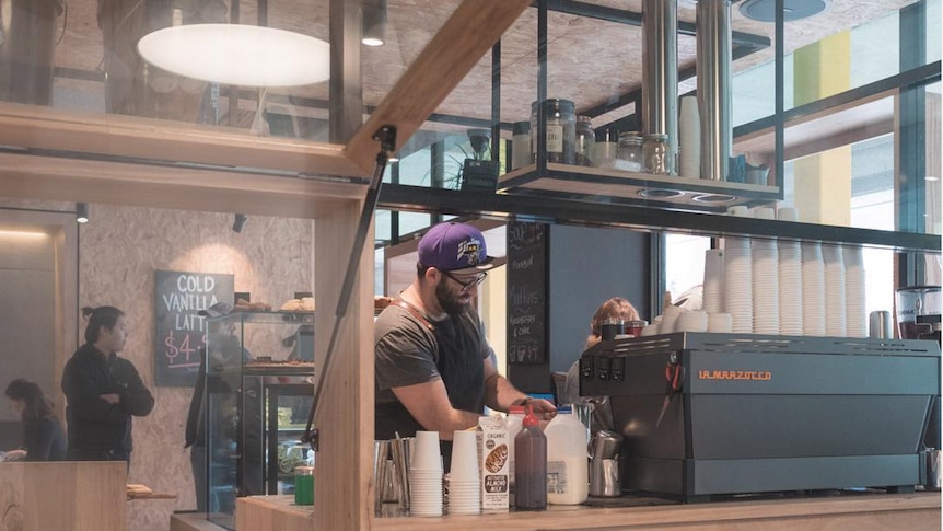 A man makes coffee at a cafe coffee machine. 