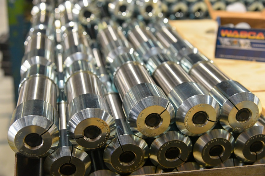 Small silver hollow cylinder shaped bolts stacked two-high on a table.