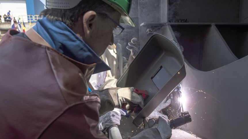 Man welding on ship's hull.