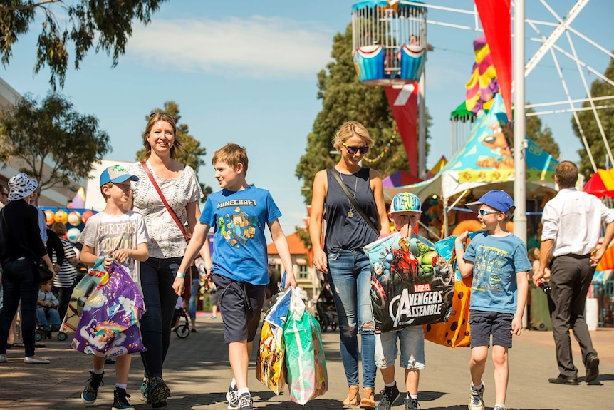 Children and adults walk towards sideshow alley at the show