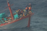 indonesian fishermen in lifejackets aboard a semi-submerged vessel wave their hands