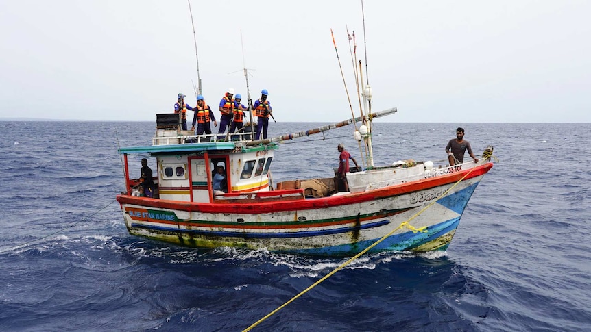 A Sri Lankan trawler being towed with people wearing life jackets aboard.