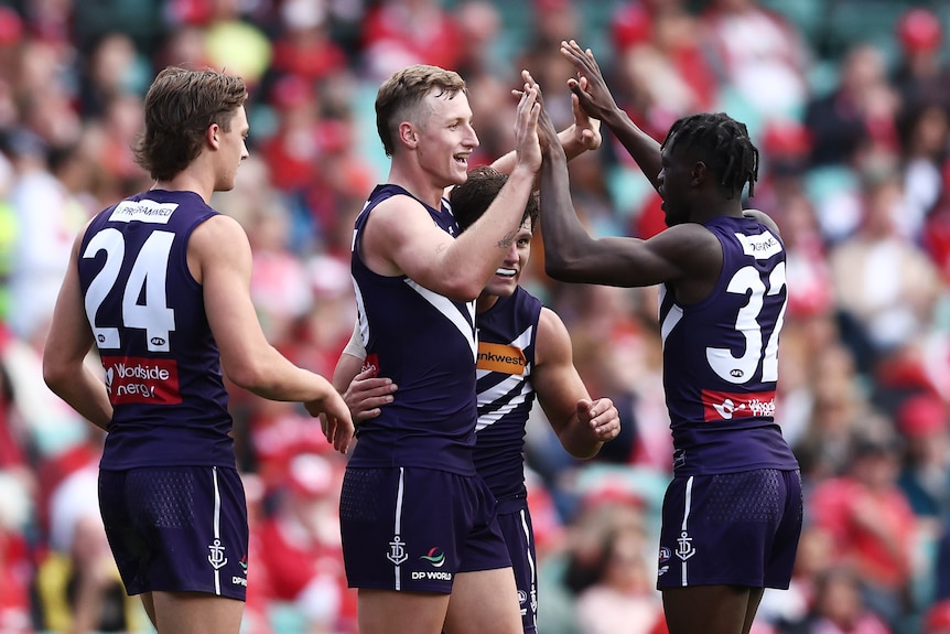 Josh Treacy is congratulated by his Fremantle teammates with hugs and high fives