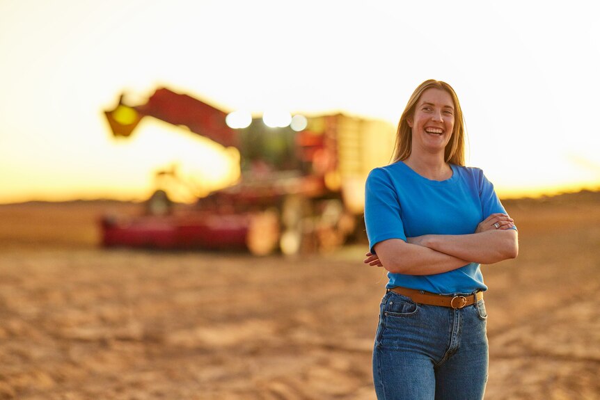 Renee Pye stands with a harvester in the background. 