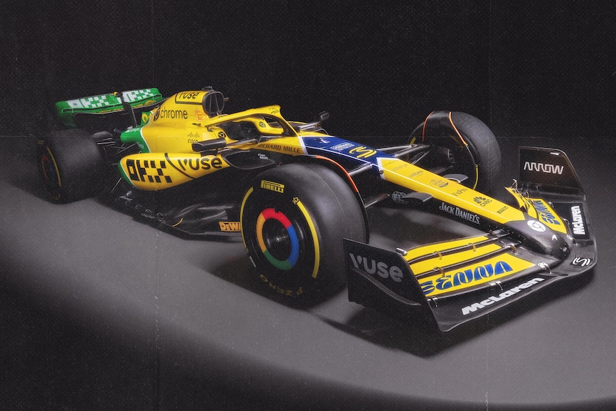 An F1 car in a promotion photo, with a green, yellow and blue painted livery