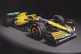 An F1 car in a promotion photo, with a green, yellow and blue painted livery