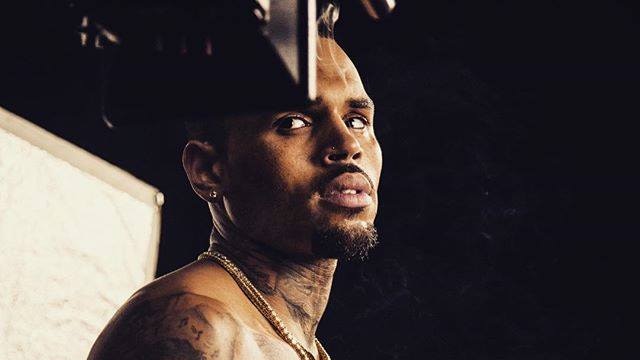 A portrait of Chris Brown at waist-height shows him with no shirt on and plenty of tattoos.