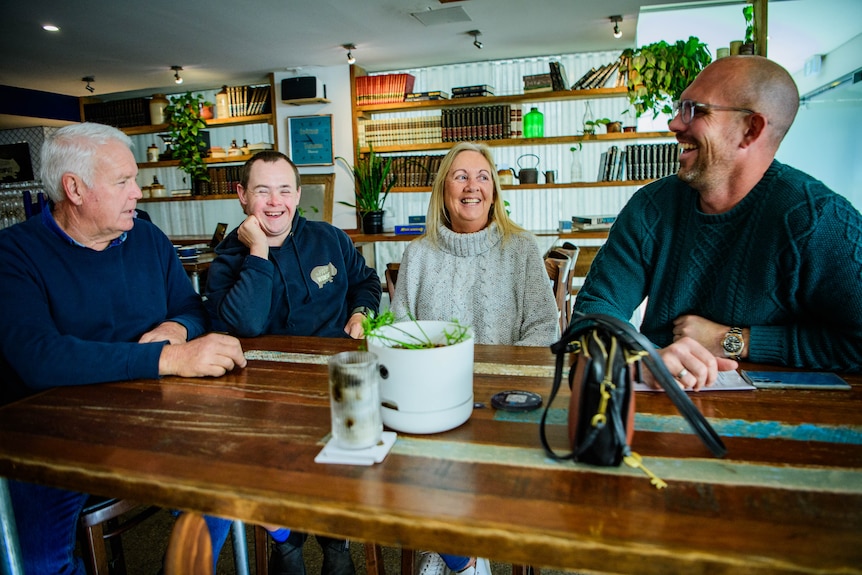 Four white people sitting around a table at a cafe smiling and laughing