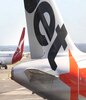 一架澳洲航空喷气式飞机经过一架捷星飞机，机尾上的标志清晰可见。