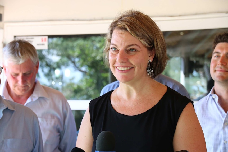 Marie-Clare Boothby stands in front of a microphone at a press conference.