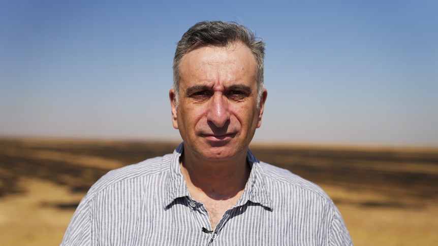 Kamalle Dabboussy stands in front of a field in Syria.