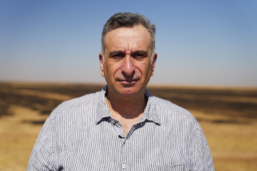 Kamalle Dabboussy stands in front of a field in Syria.