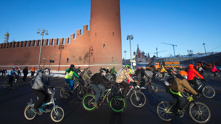 Cyclists ride their bikes along the embankment of the frozen Moskva River.