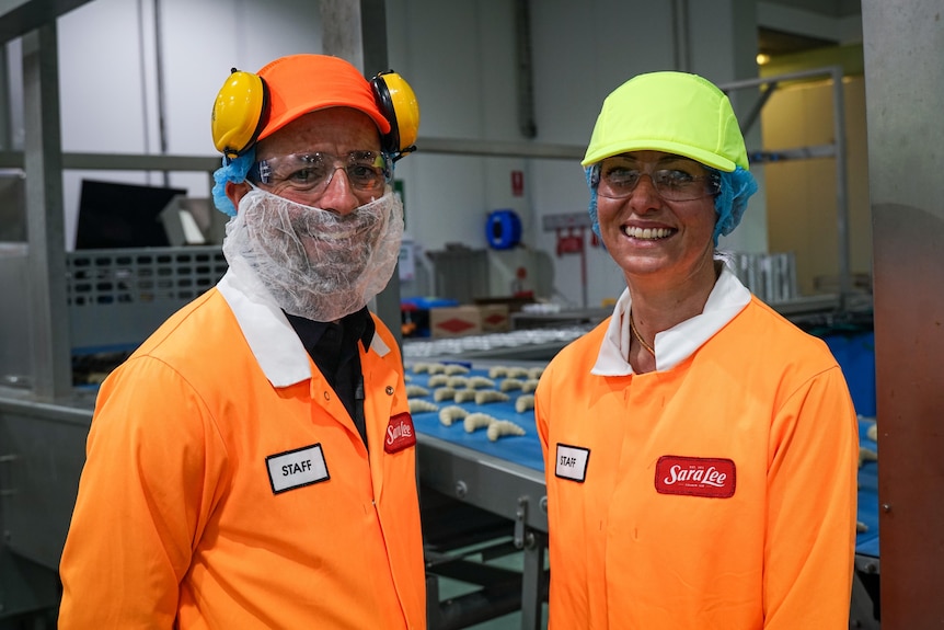 A man and woman in protective gear in a factory.