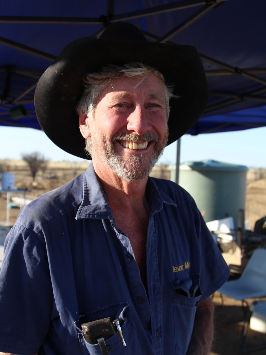 A smiling man in a blue shirt and black hat
