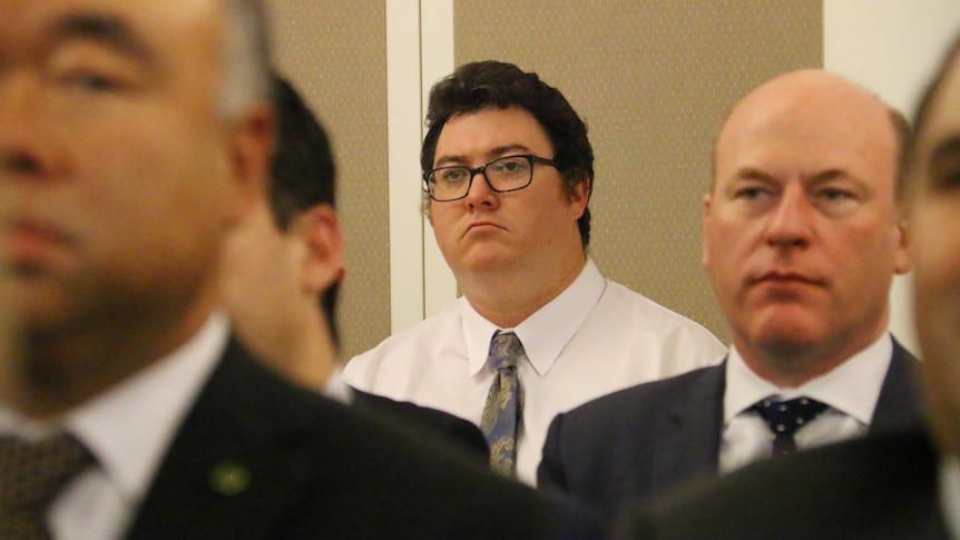 Conservative Liberal backbencher George Christensen MP stands at the back of a room looking sad