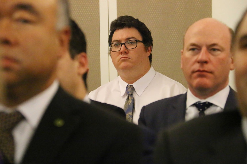 Conservative Liberal backbencher George Christensen MP stands at the back of a room looking sad