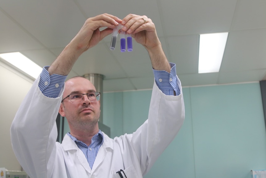 Hans holds up purple test tubes.