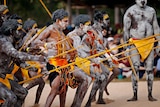 Indigenous Australians in traditional dress performing a traditonal dance during an opening ceremony