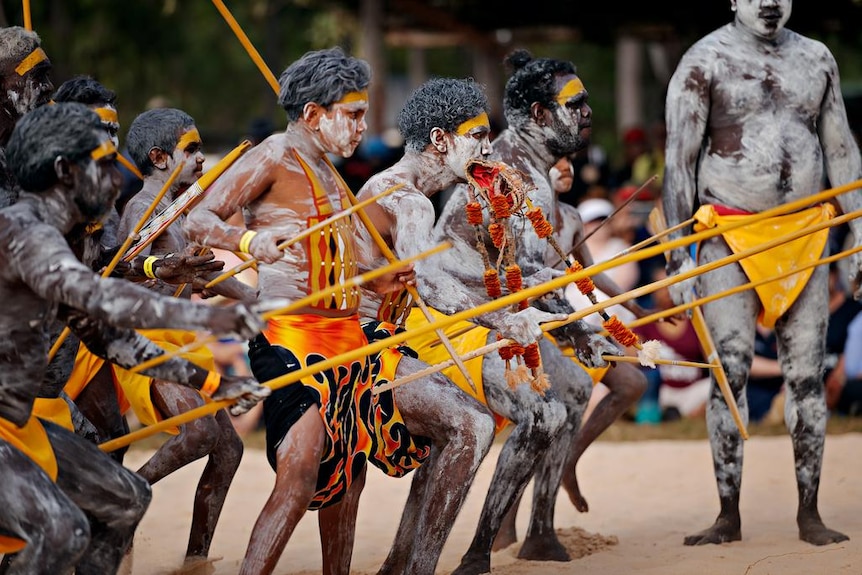 Indigenous Australians in traditional dress performing a traditonal dance during an opening ceremony