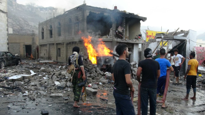 People gather at the site of a suicide car bombing outside Yemen's presidential palace.