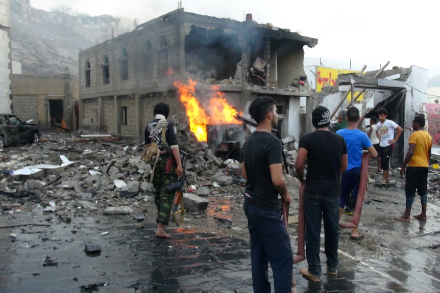 People gather at the site of a suicide car bombing outside Yemen's presidential palace.