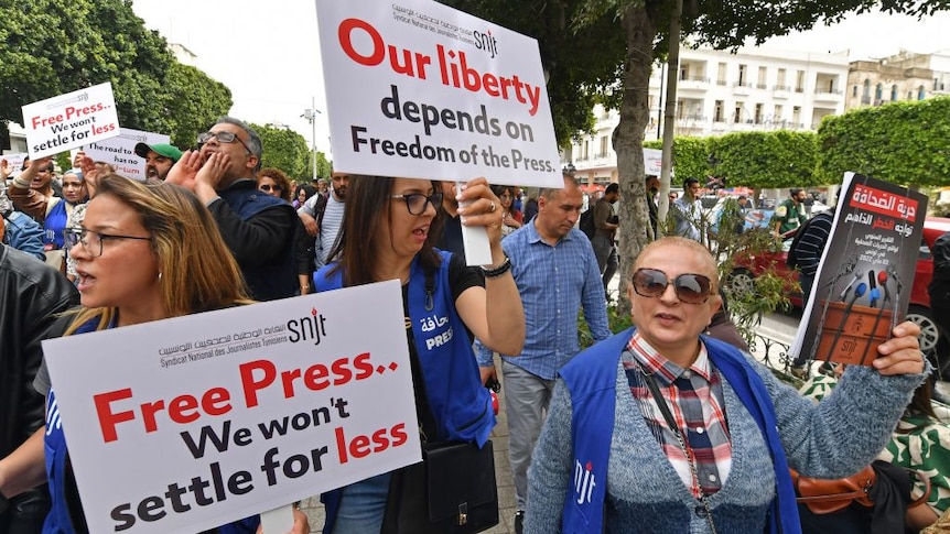 Tunisian journalists hold signs during a protest demanding press freedom