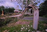 A power pole made of concrete and steel is broken and bent by winds