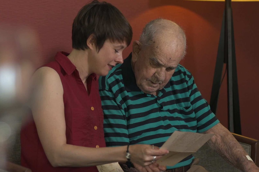 Katrina Elliot Myerson and Bob Christie sitting in a chair going through Bob's POW letters