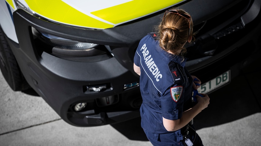 A female paramedic walks past an ambulance parked outside the Royal Hobart Hospital.